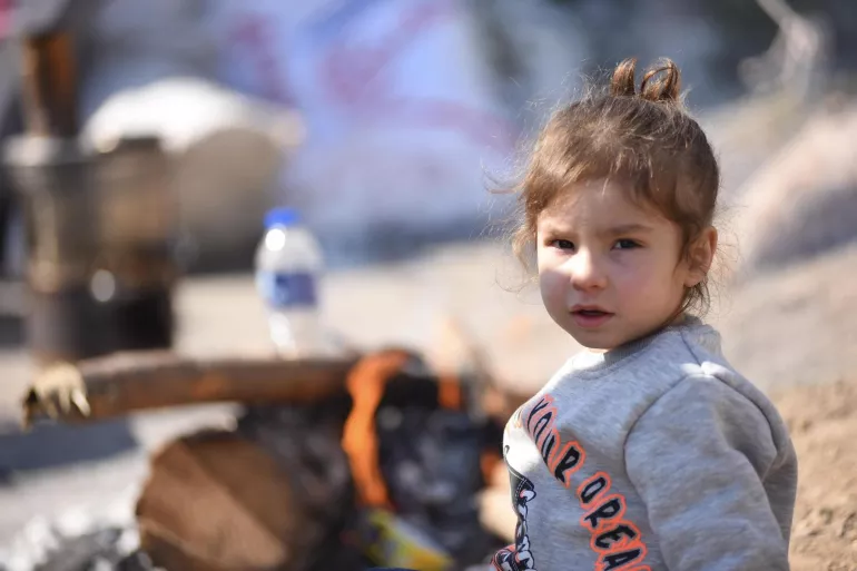 Момиче се топли до огън във временните лагери след опустошителното земетресение в Турция