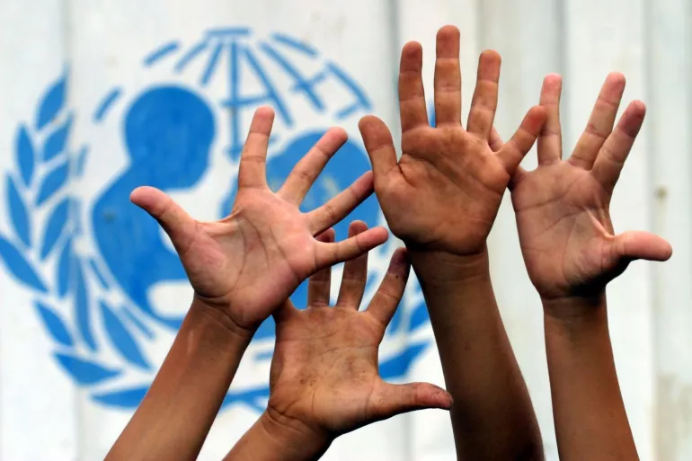Hands raised in the air in front of UNICEF's logo 