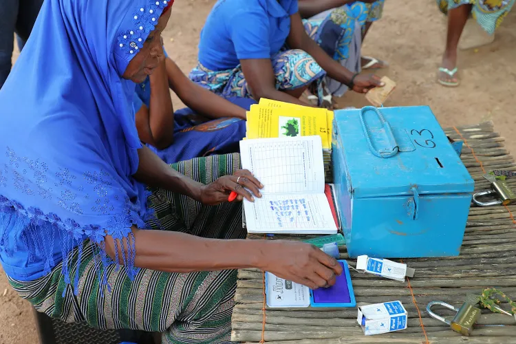 Ebou N&eacute;a, secr&eacute;taire du VSLA Yissono de Naton met le tampon sur le carnet d&rsquo;une des membres du groupe qui vient de cotiser