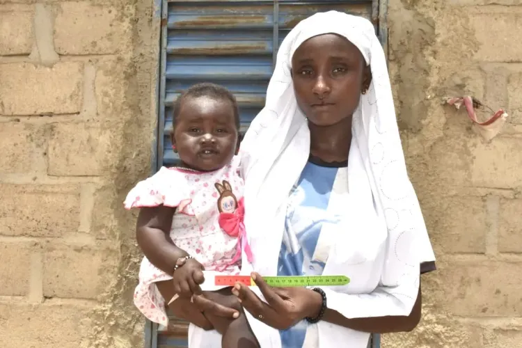 Djamila utilise le bracelet MUAC pour mesurer le p&eacute;rim&egrave;tre brachial de sa fille Fatim, &acirc;g&eacute;e de neuf mois, &agrave; Dori