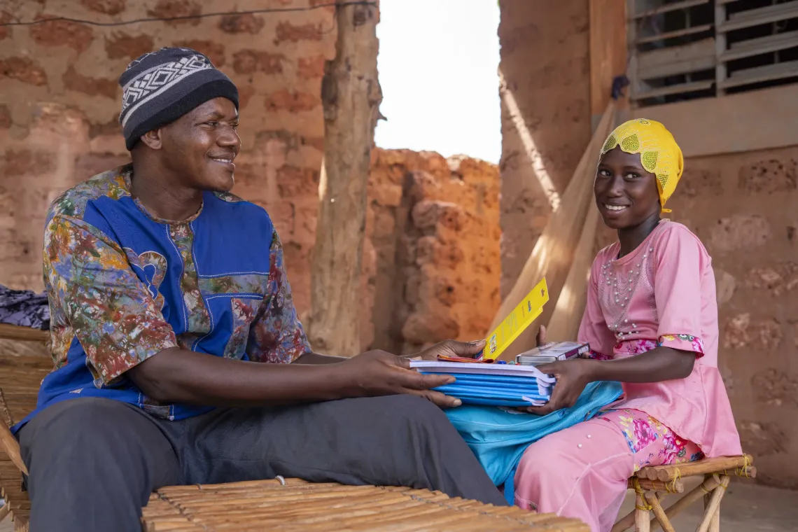 Adjara, une fille d&eacute;plac&eacute;e de 11 ans, montre son kit scolaire &agrave; son oncle Oumarou Sidibe &agrave; D&eacute;dougou, Burkina Faso.