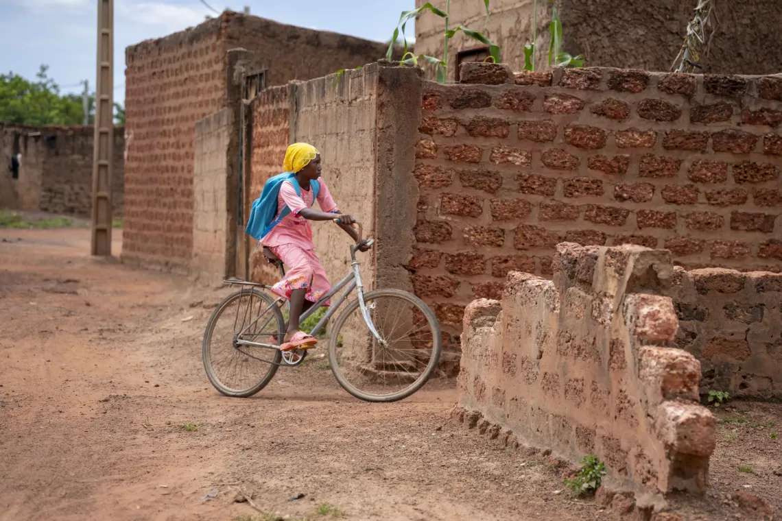 Adjara, une fille d&eacute;plac&eacute;e de 11 ans, rentre de l&rsquo;&eacute;cole &agrave; v&eacute;lo &agrave; D&eacute;dougou, Burkina Faso