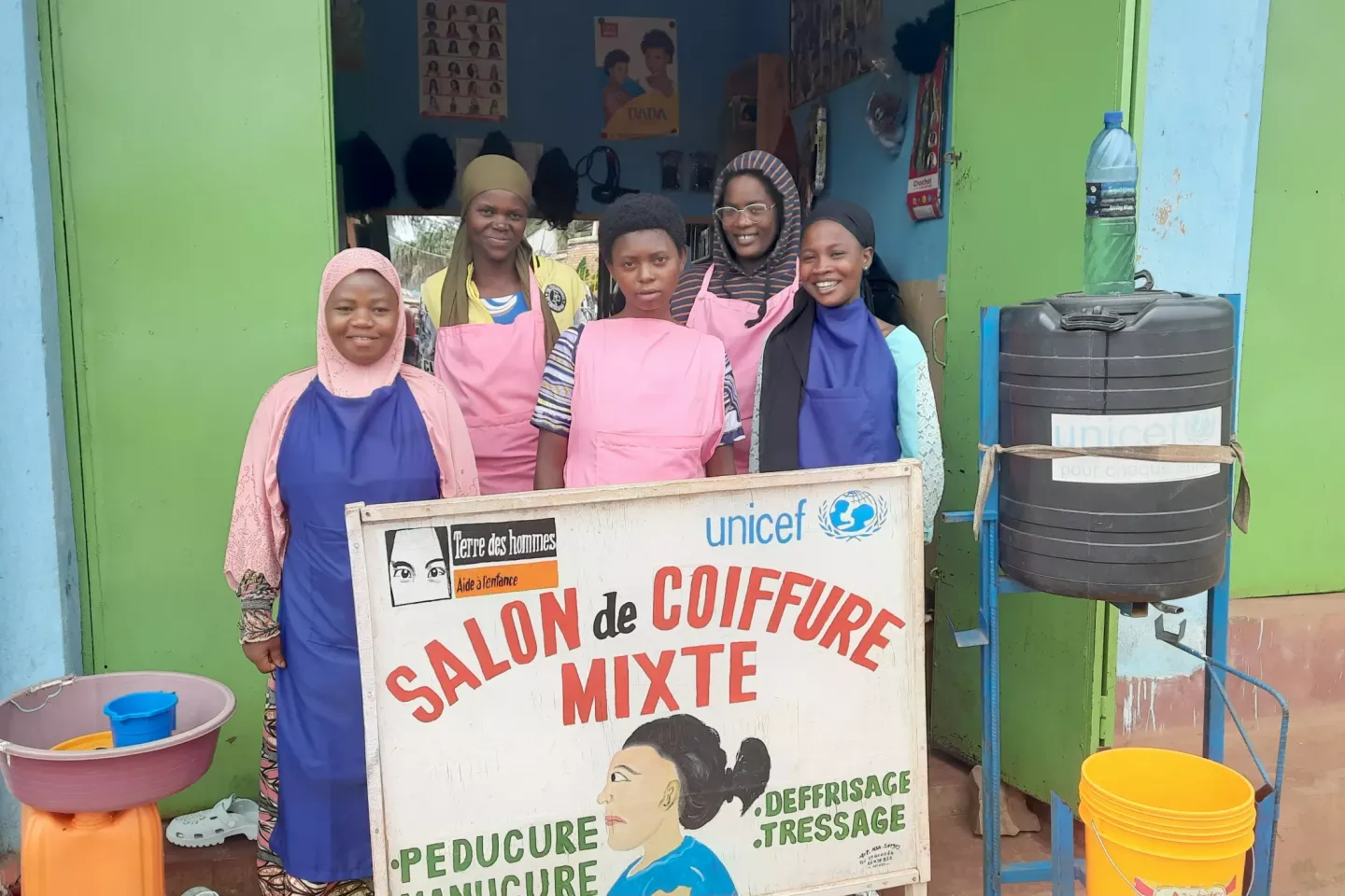 Anifa is in the process of styling someone's hair in a salon she runs with other girls trained in the hairdressing.