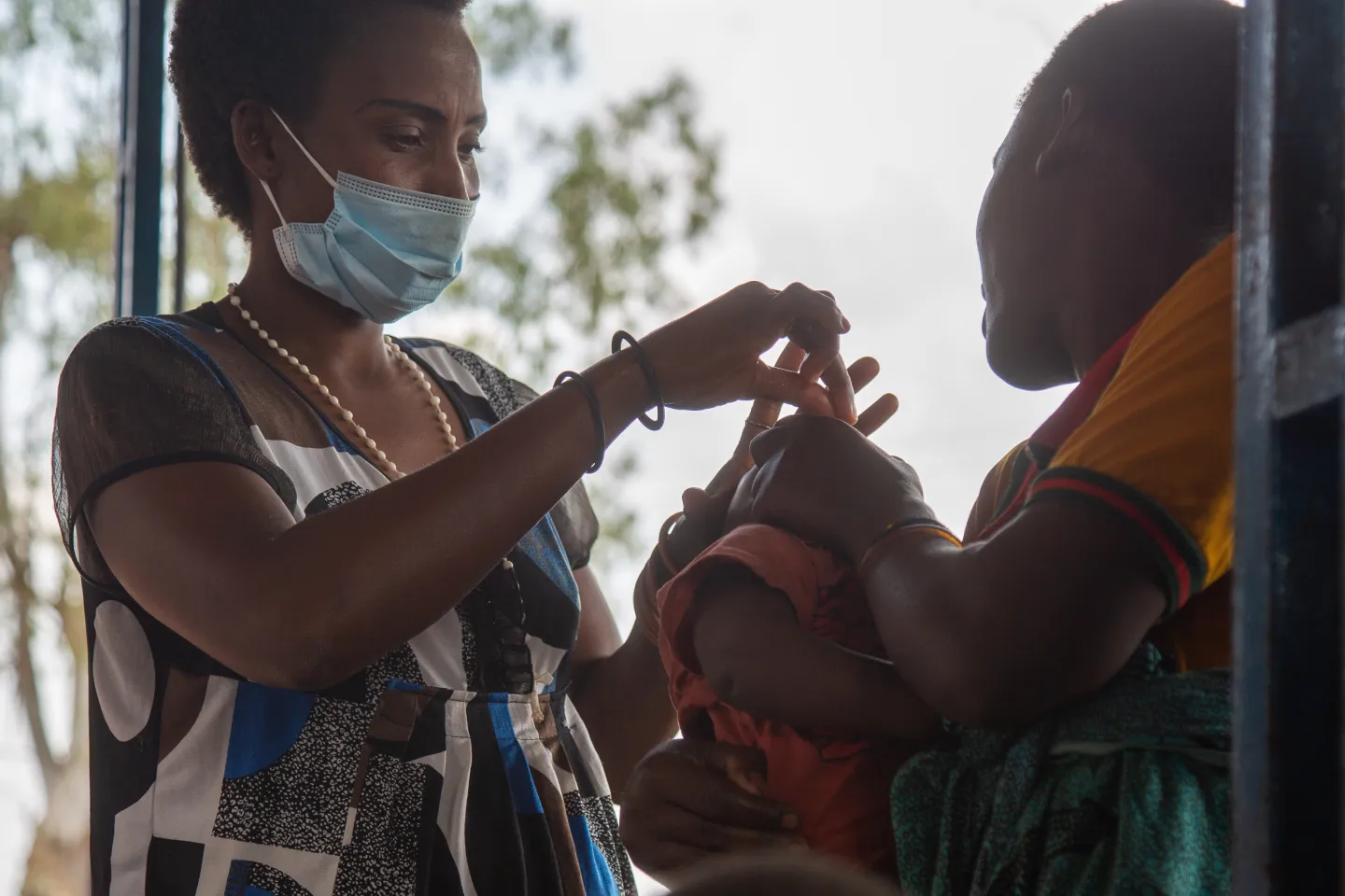 A community health worker gives a child drops with vitamin A