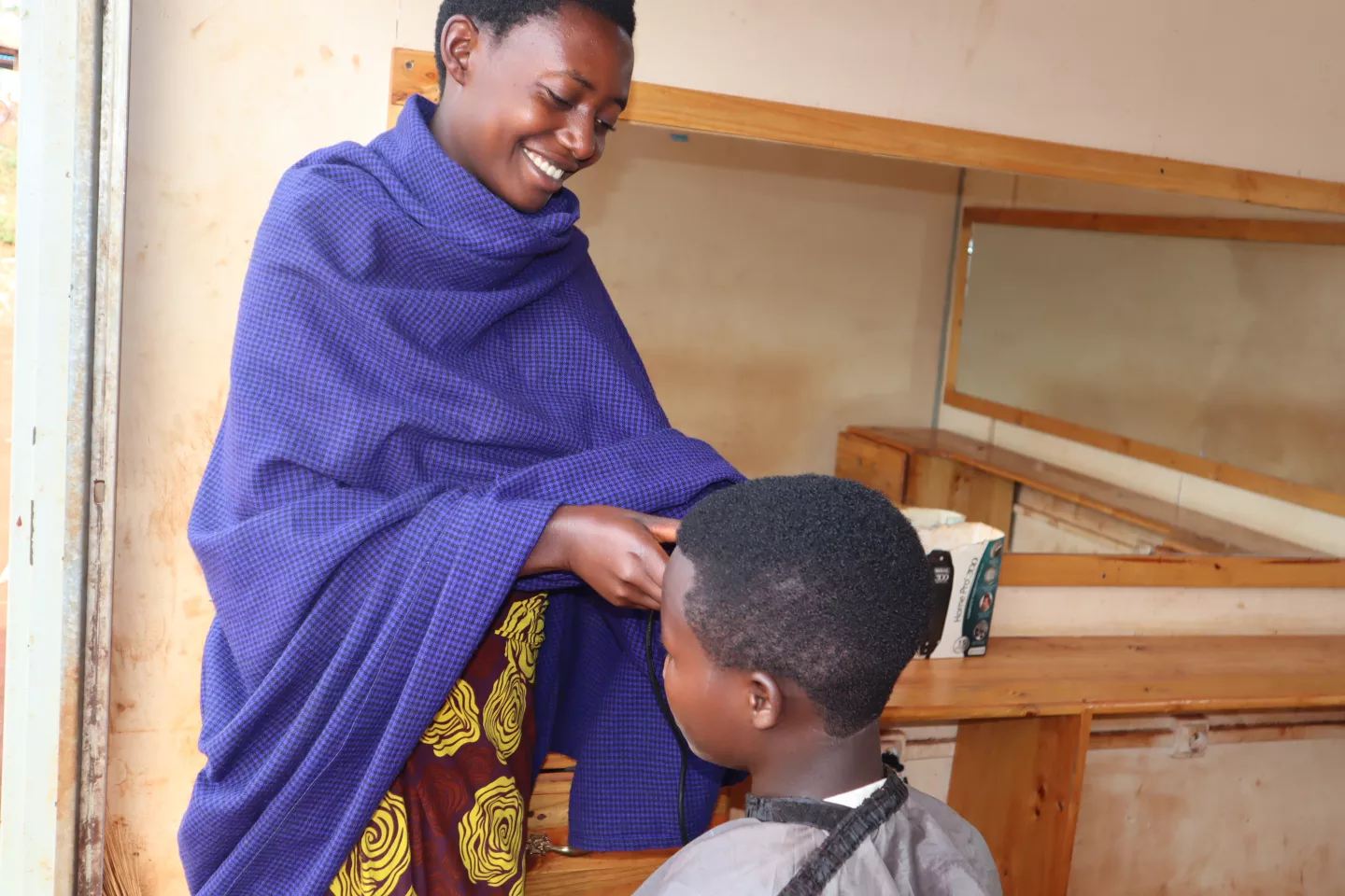A survivor of human trafficking cuts the hair of one of her clients as a result of her new income-generating activity, which has allowed her to reintegrate into her community following her experience 