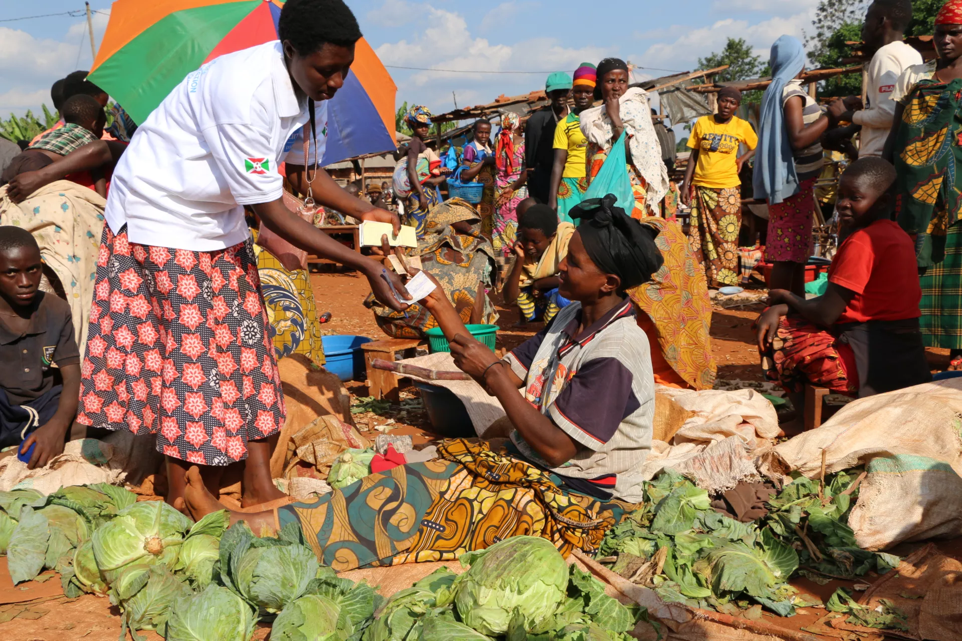 A tax collector (Adidja) giving a receipt to a cabbage seller at the Rutoke market in Mungwa, commune Gitega, province Gitega.