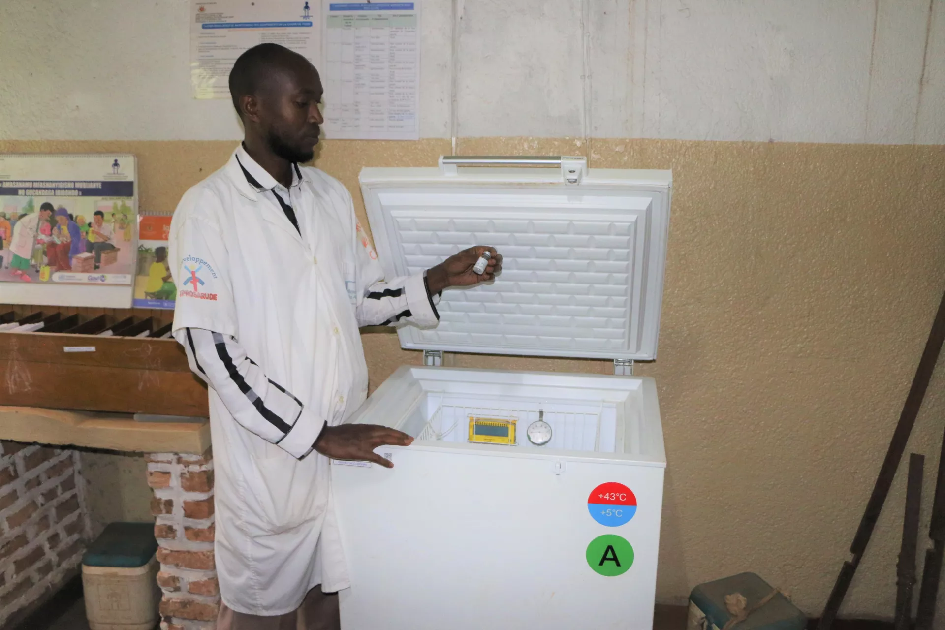 A nurse is examining the vaccines stored in the refrigerator at CDS Ruhororo.