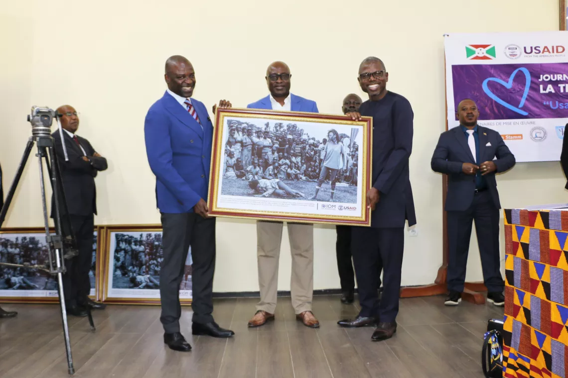 UNICEF Representative in Burundi, Dr. John Agbor (left); UN Resident Coordinator in Burundi, Damien Mama (right); and OIM Representative in Burundi (center), showing the photo winner of the USDAID 2022 photo contest.