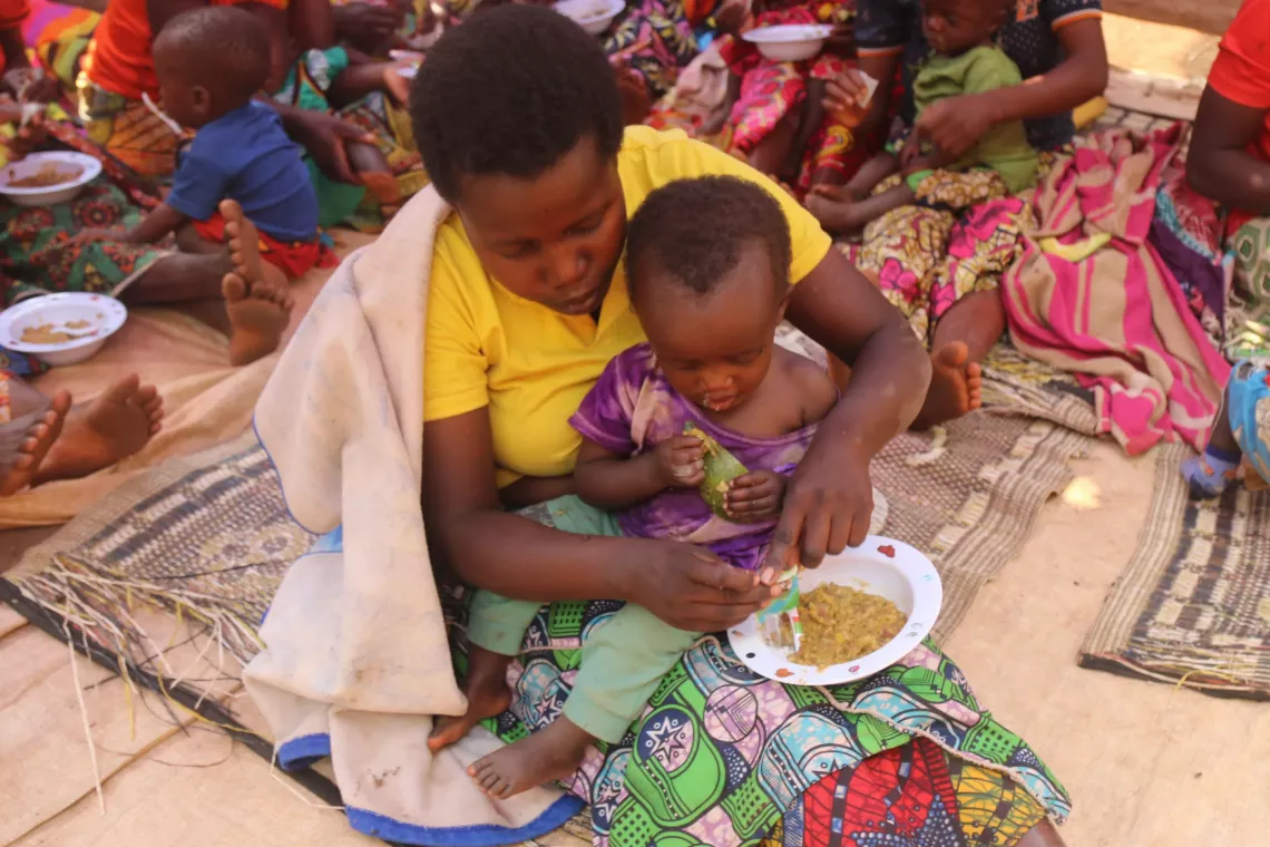 Une m&egrave;re ajoute de la poudre de micro-nutriments dans l'assiette de son enfant, chez Miburo Godelieve lors d&rsquo;une seance de FAN.