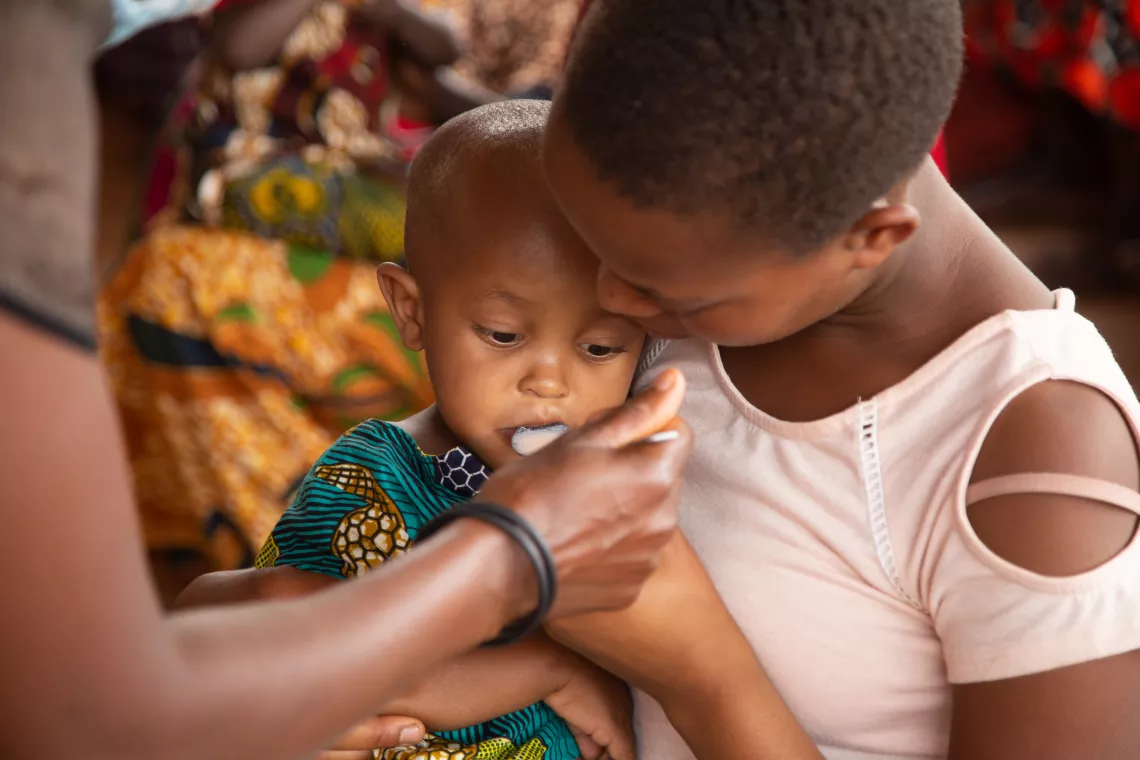 A two-year old girl receives a spoonful of a deworming drug.