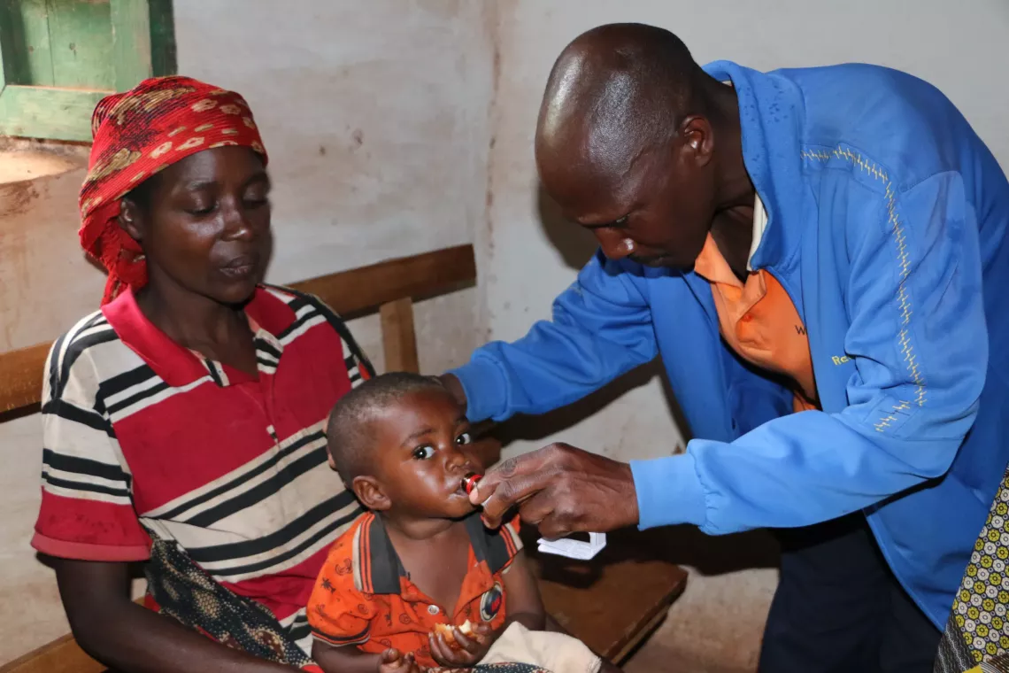 A community health worker deworming a child with Albendazole.