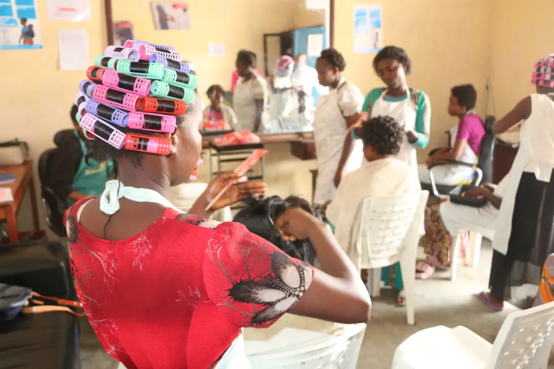 Une jeune fille encadr&eacute;e dans l'ONG UCBUM et qui suit une formation en coiffure en train de peigner une cliente dans un salon de beaut&eacute;. 