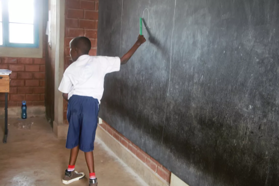 A child living with a physical disability reads on a blackboard designed to be accessible to all