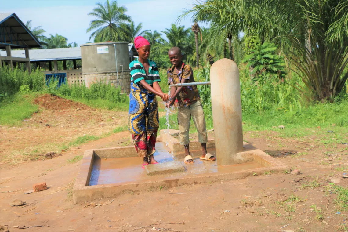 Un enfant et une femme se lavent &agrave; la borne fontaine aliment&eacute;e par le r&eacute;servoir du march&eacute; de Gatete en commune Rumonge. L'installation a &eacute;t&eacute; financ&eacute;e par le Gouvernement du Japon.