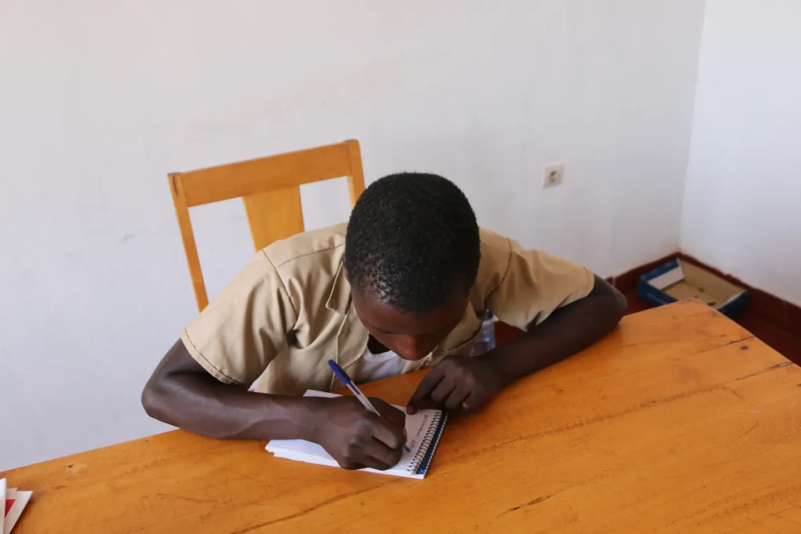 A 16-year-old boy from Rambo Hill, Kirundo Commune, studying after receiving support from social workers through funding from Barrie Landry.