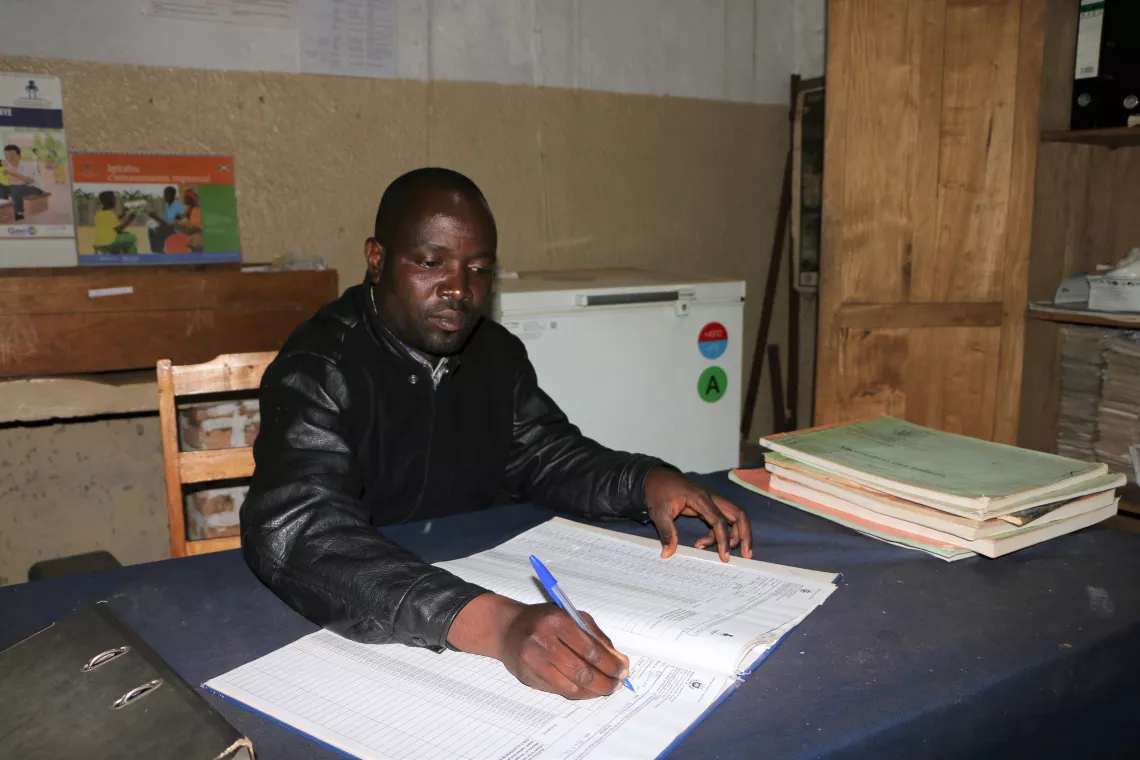 The manager of the Ruhororo health centre is taking refrigerator temperatures.                                      