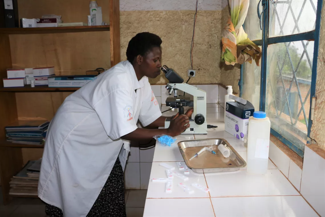     A nurse is running medical tests under a microscope.