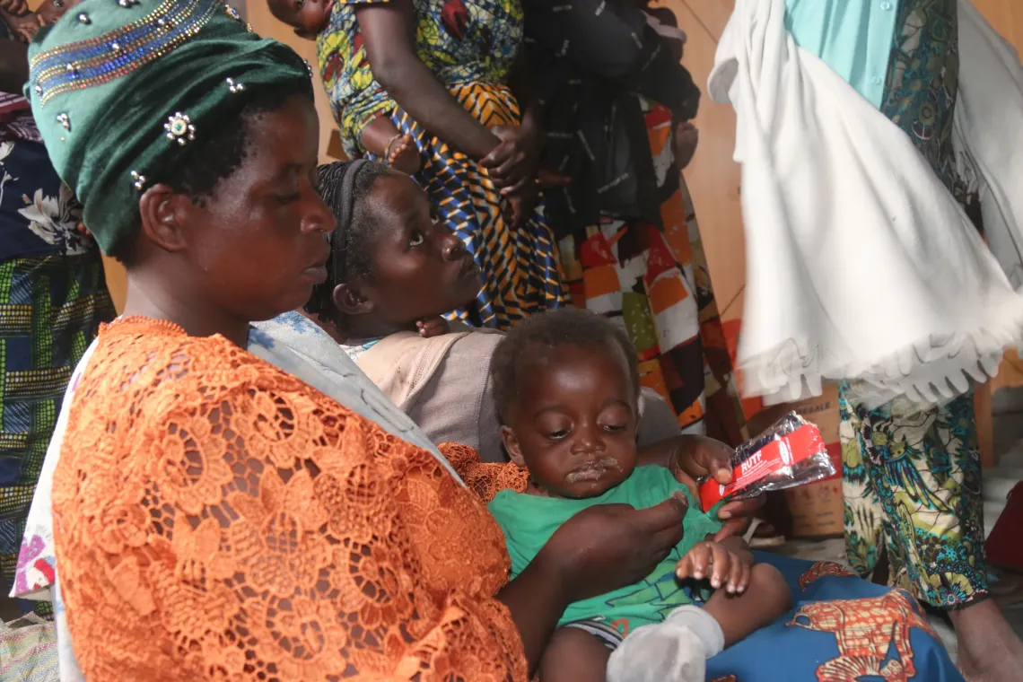Nguza Zuena, with her infant, comes to receive her first ration of Plumpy'Nut..