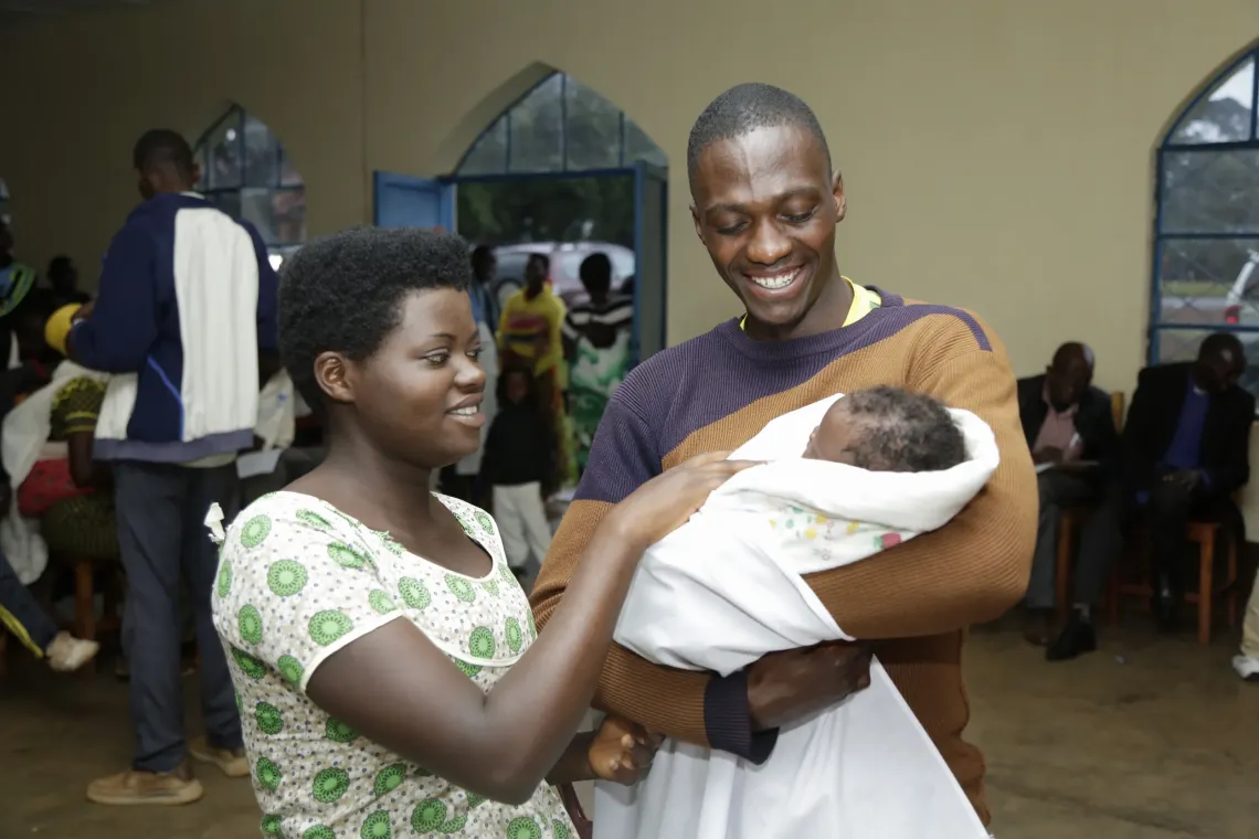  Gilbert and Florence looking at their child, fully vaccinated and healthy 