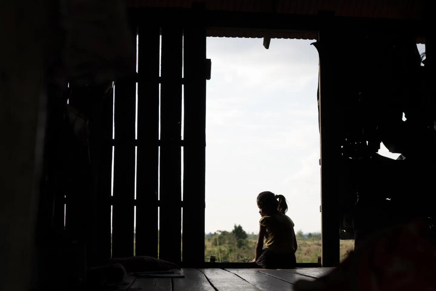 Toch Soknea sits in the doorway of her honme in Snoul District