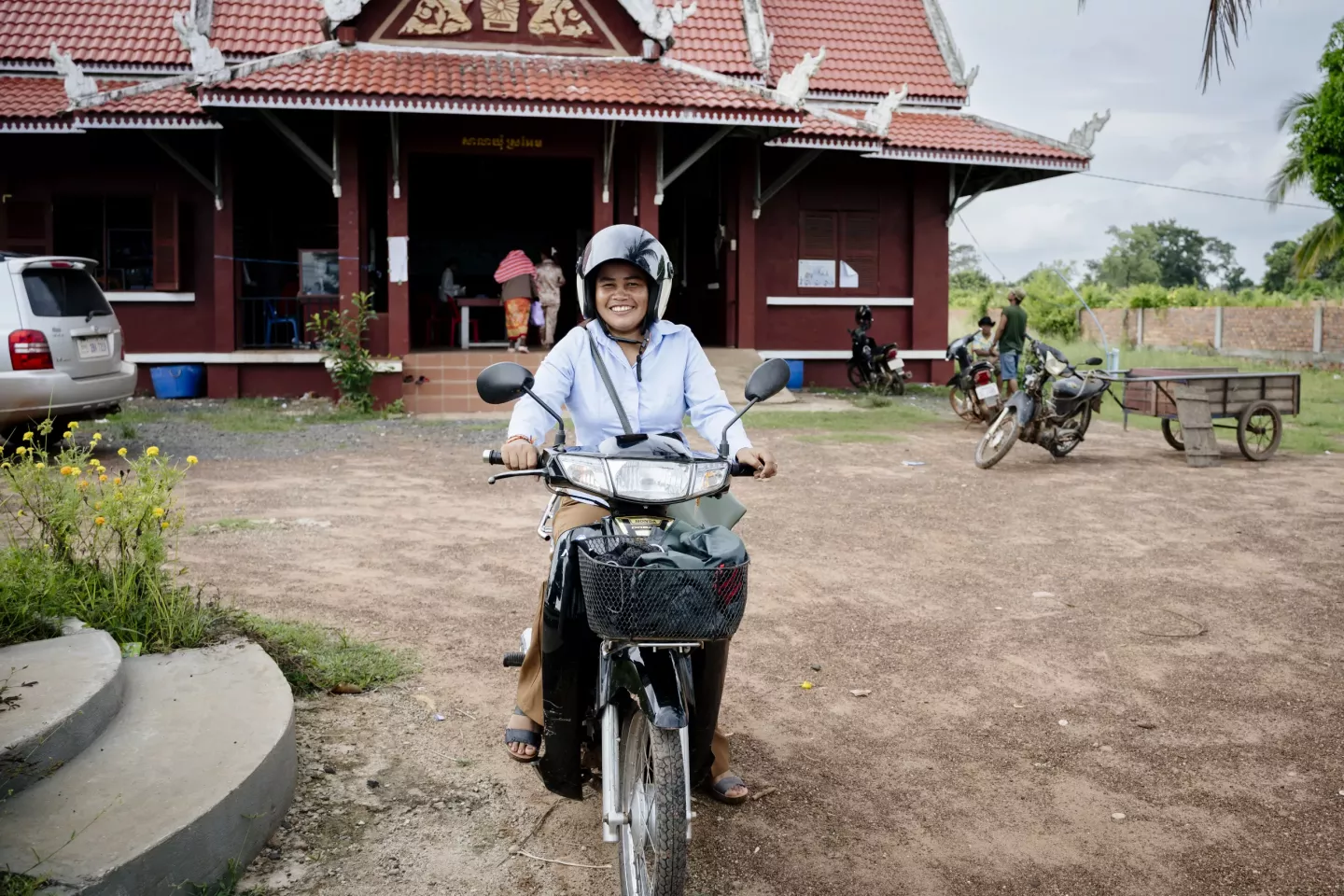 Ms. Buor Sak, the second deputy chief of Sraem Commune in Choam San District, Preah Vihear Province, rides her motorcycle to visit and assess poor families eligible for the government's Family Package programme.