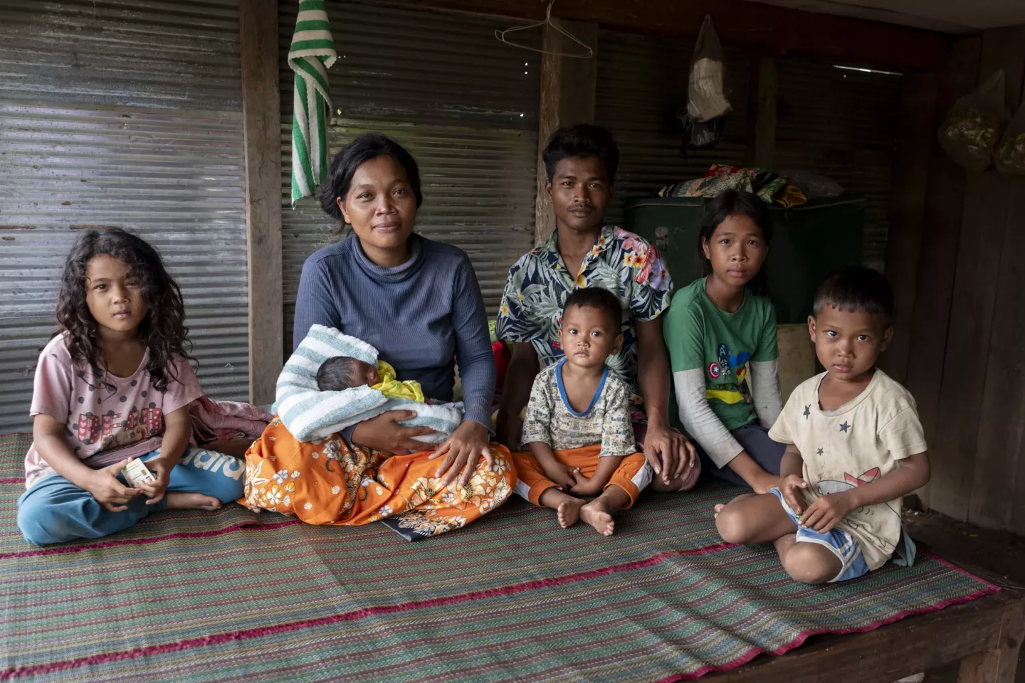A family photo of (from left to right) Horn Sreynoch, 7, her mother Ms. Van Rath, 30, holding eight-day-old Moeur Sreyneth, and her father Thoem Moeur, 24, Moeur Thavoan, 3, Horn Pisey, 13, and Vid Naveath, 5, at their home in Sraem Commune, Choam San District, Preah Vihear province. Van Rath is a Family Package beneficiary for pregnant women and children under two years old.