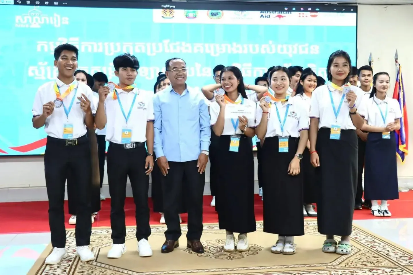 សិស្សានុសិស្សប្រាំនាក់មកពីគ្រួសារជនជាតិភាគតិចនៅវិទ្យាល័យ ហ៊ុន សែន មណ្ឌលគិរី បង្ហាញគម្រោងរបស់ពួកគេប្រកបដោយមោទនភាព &ldquo;ស្ម័គ្រចិត្តដើម្បីភាពញញឹមនៃយុវជន&rdquo; ដែលមានគោលដៅទប់ស្កាត់ការបោះបង់ចោលការសិក្សាមុនពេលកំណត់ដែលបណ្តាលមកពីការរៀបការមុនអាយុ ។ ក្រុម -ដែលមាន ឌីណា រតនៈកែវ (១៦), វ៉ាន់គ្រី សុរិន (១៨), កែវ ស្រីណុច (១៦), ឃួន មុនីរ័ត្ន (១៦), និង ស្លេ កូឡេត (២០) - ឈរជាមួយនាយកសាលារបស់ពួកគេ គឺ លោក ឃុត តូ បន្ទាប់ពីទទួលបានចំណាត់ថ្នាក់លេខ ២ ក្នុងការប្រកួតជជែកដេញដោលថ្នាក់តំបន់ ។