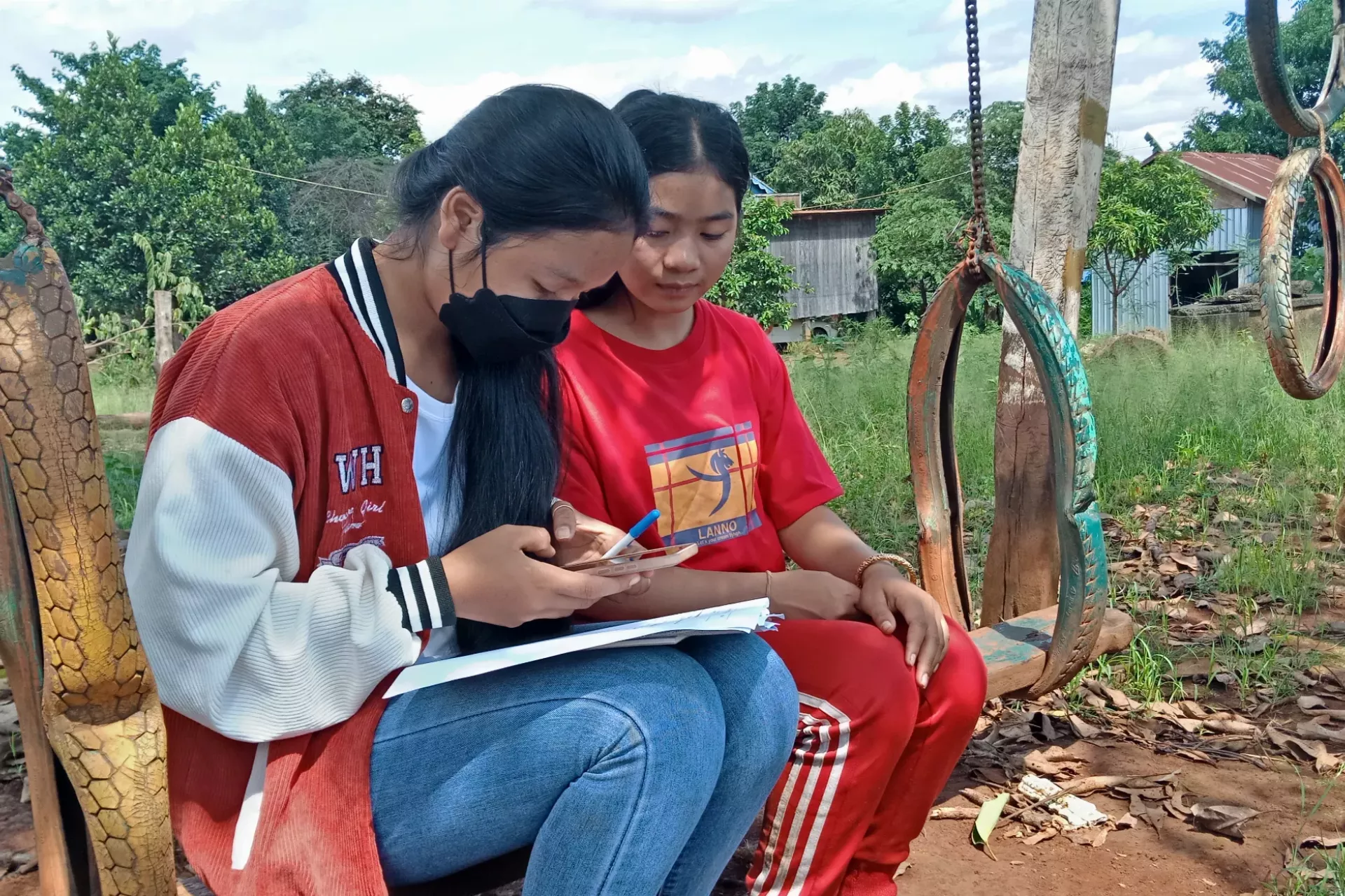 Toch Nangra (left) and Yong Nak (right) sit under the trees in a local schoolyard after attending a Strong Family session. 