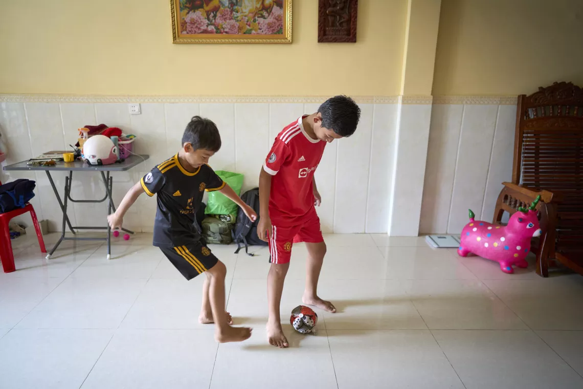 Two boys in soccer uniforms playing with a ball inside
