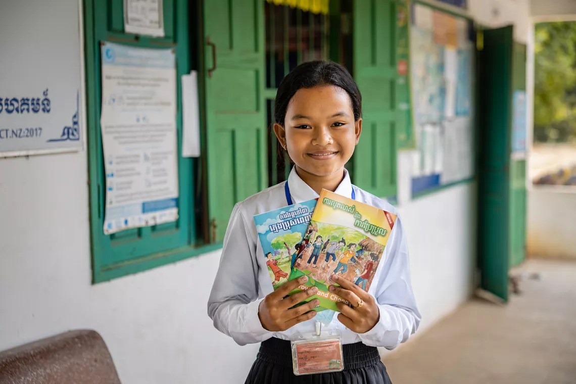 Voeurn Sreysras, 12, a Grade 6 student at Ang Run Primary School, shows the Growth and Changes and To Become and Young Man booklets after proudly sharing her knowledge that she learned from school and at home about menstrual hygiene to the UNICEF staff on her school campus in Tramkak District, Takeo Province, Cambodia. 