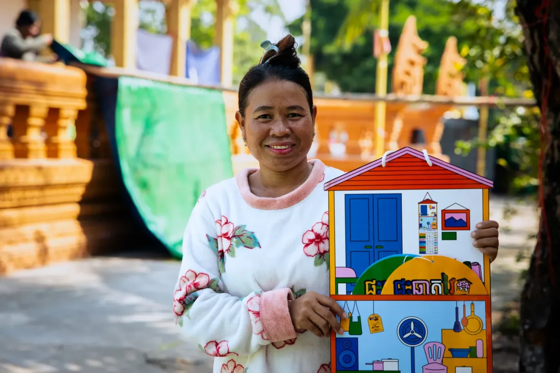 Touch Luot, 40, a mother living at Sampov Loun Pagoda displacement site, holds a smart home kit used in nurturing care parenting sessions to show how parents can better care for their young children.