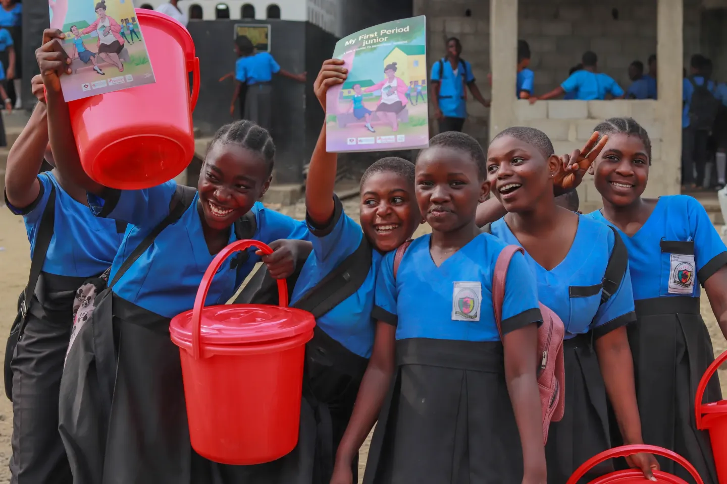 A group of adolescent girls display dignity kits and &ldquo;My First Period&rdquo; booklets inside a classroom, symbolizing access to menstrual health information and essential supplies.