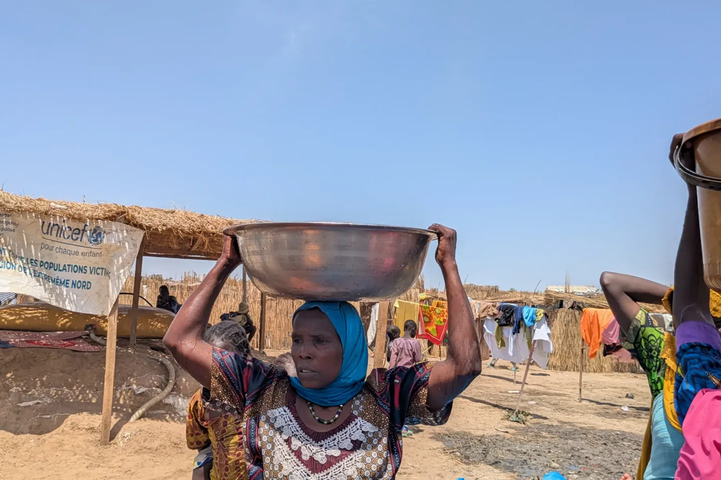 Une femme d&eacute;plac&eacute;e porte une bassine d'eau sur sa t&ecirc;te &agrave; Blangoua