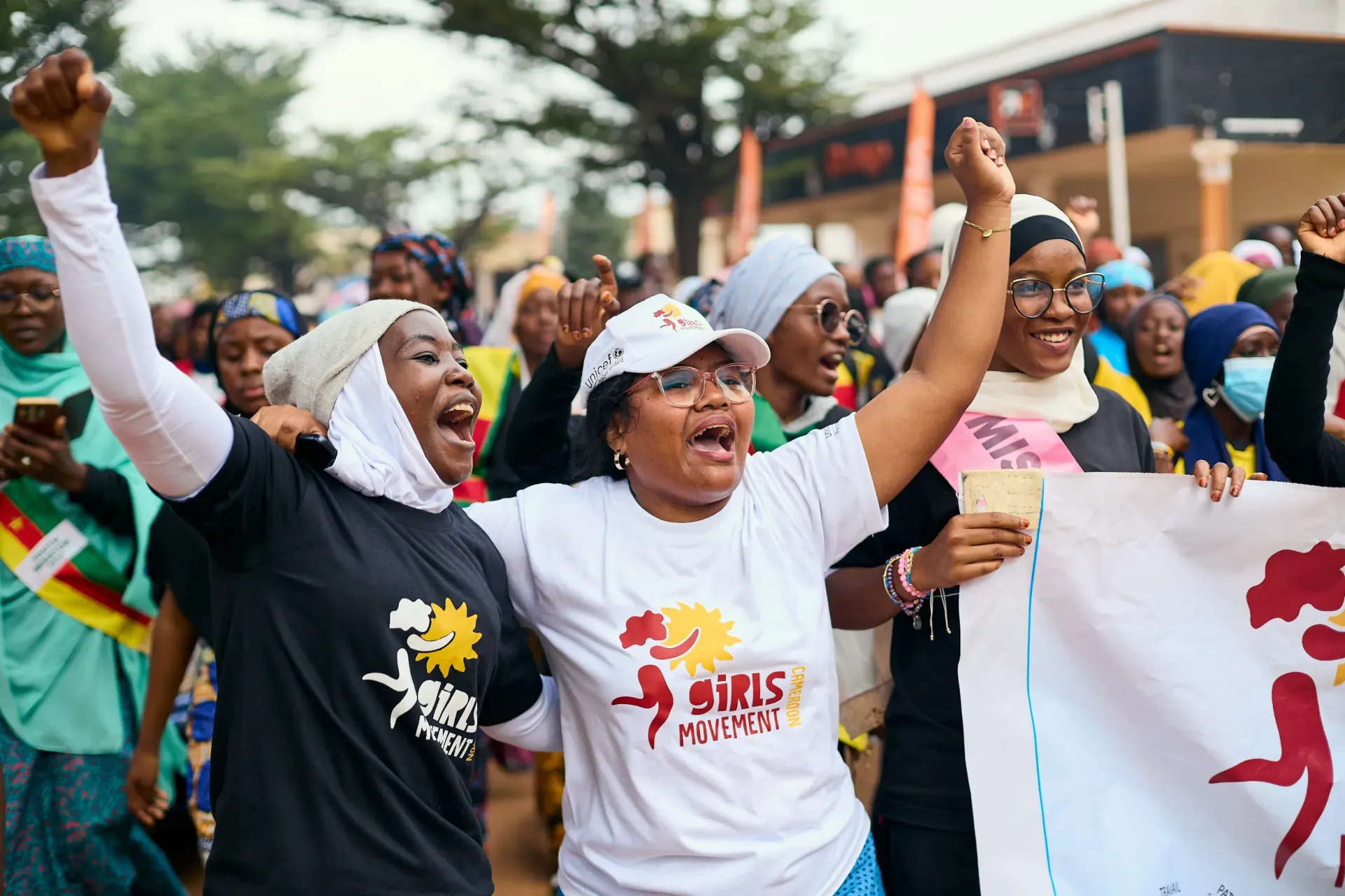 Group of people marching outdoors wearing Girls&rsquo; Movement T-shirts and raising fists in solidarity