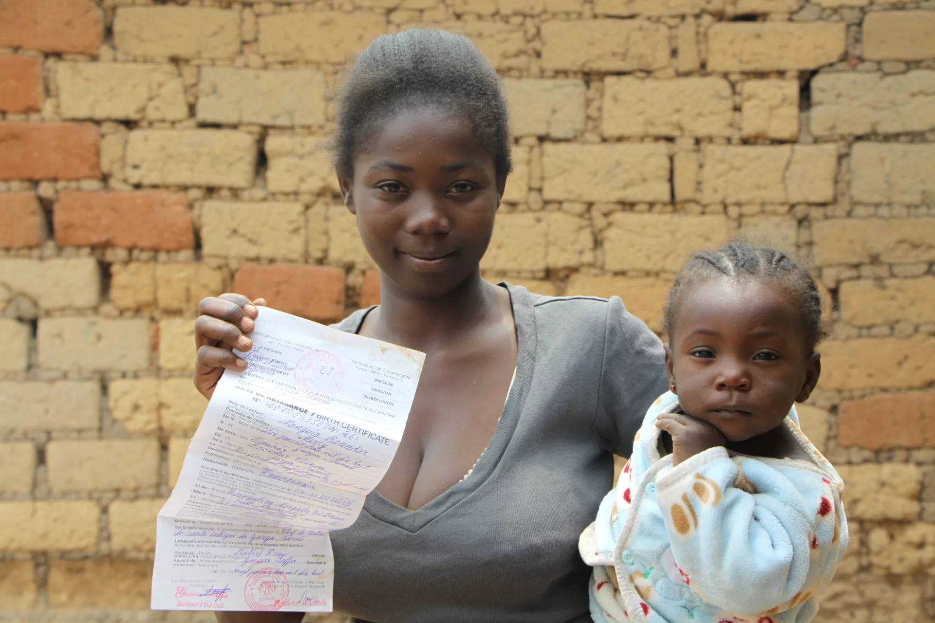 A mother holding her child with his birth certificate