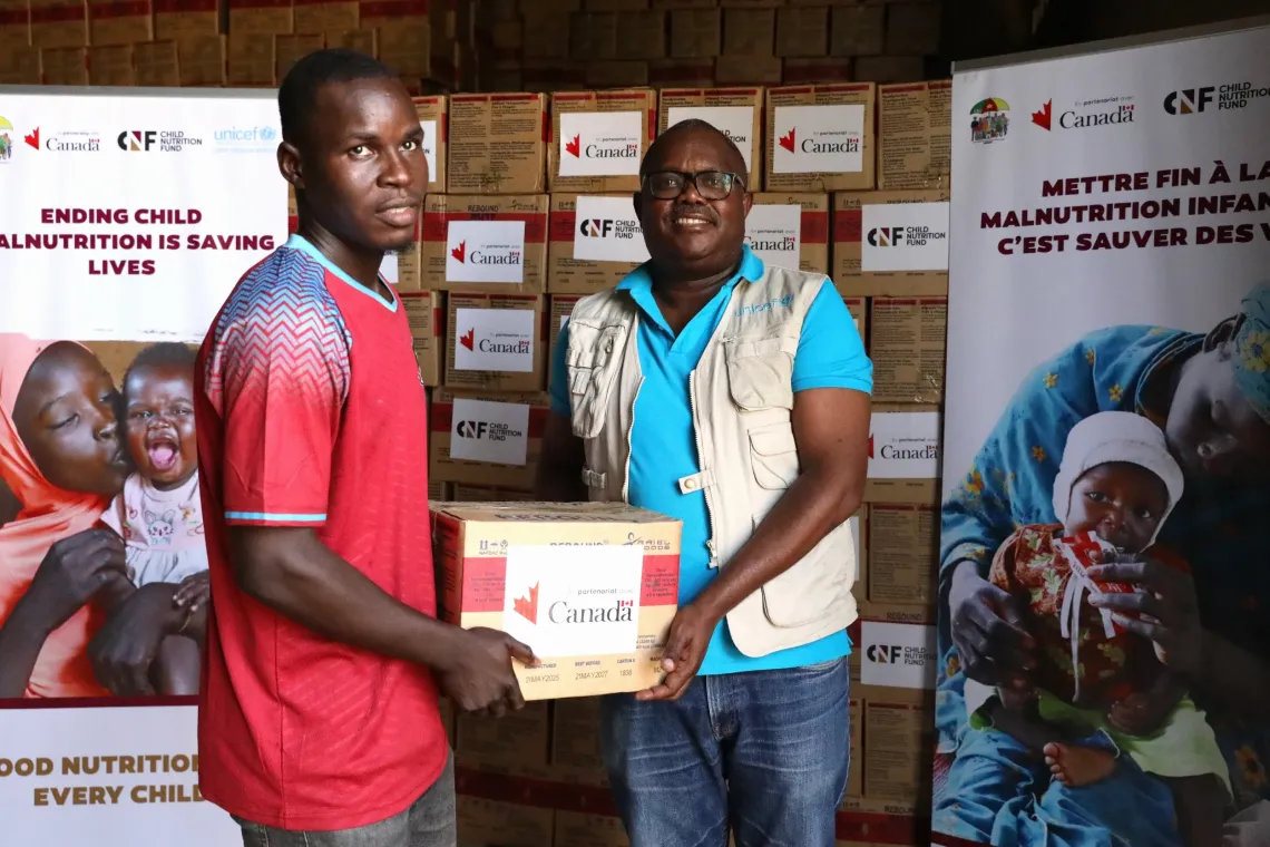 Dr Aim&eacute; Namululi de l'UNICEF remet un carton de plumpy'nut &agrave; un agent de sant&eacute;