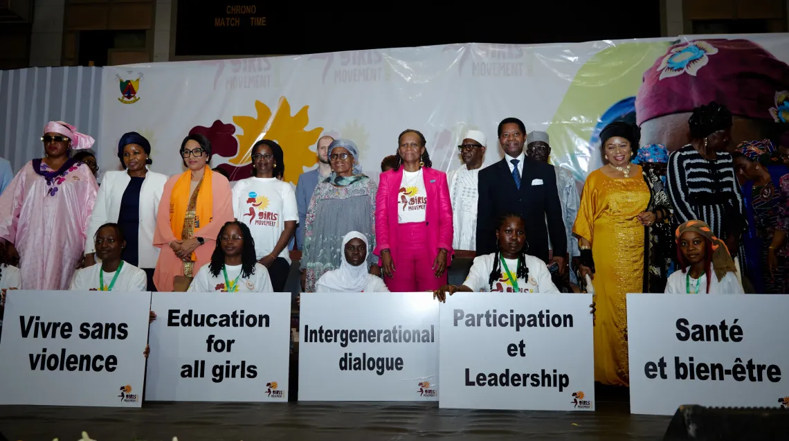 Group of people standing on stage holding signs with messages on girls&rsquo; rights, including education, leadership, and well-being