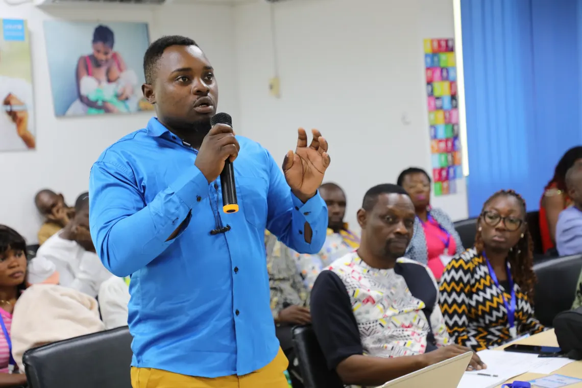 A participant speaks into a microphone during a discussion at the Media Caf&eacute; on breastfeeding, while other attendees listen and take part in the exchange.