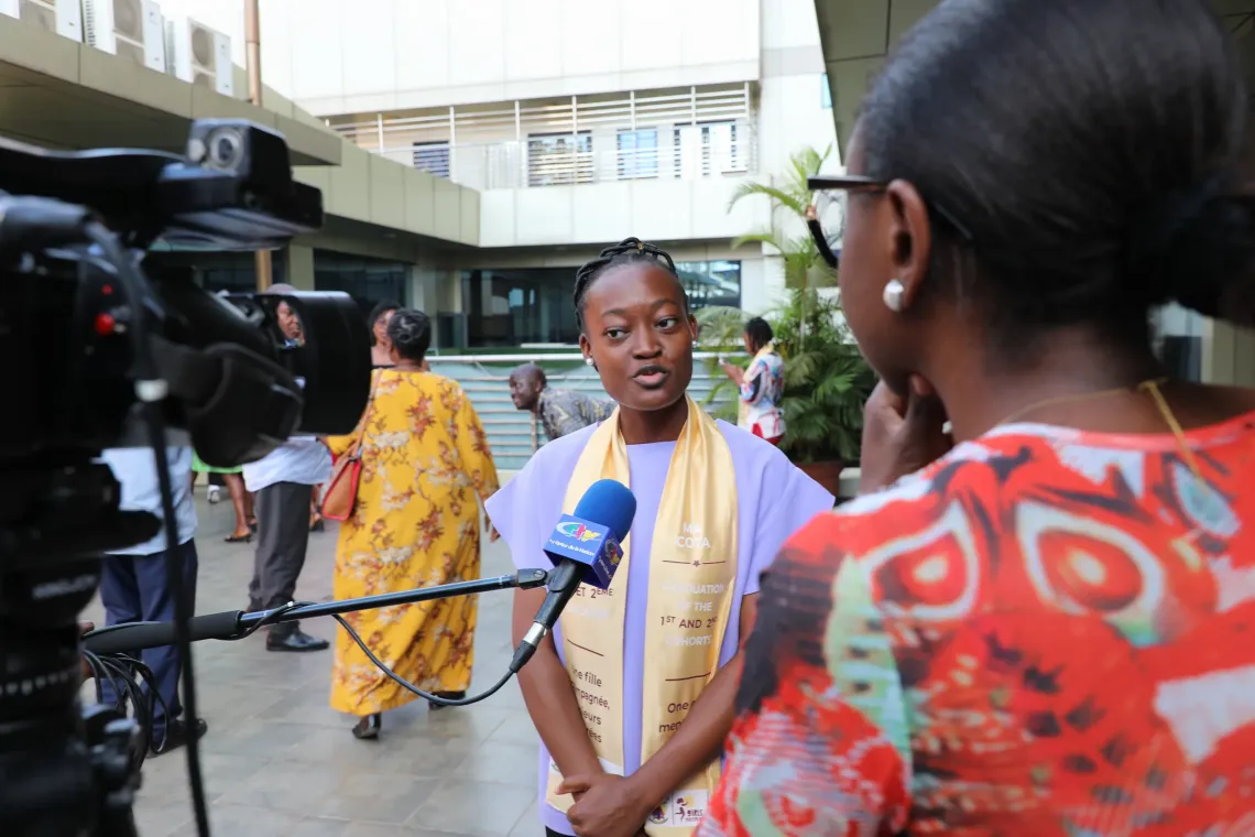 Andrea being interviewed on camera while wearing a MA COTA sash during programme event
