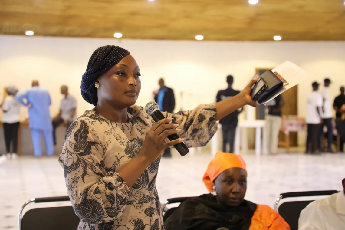 Journalist speaking into a microphone while holding notes during a discussion to support U-Reporters&rsquo; achievements