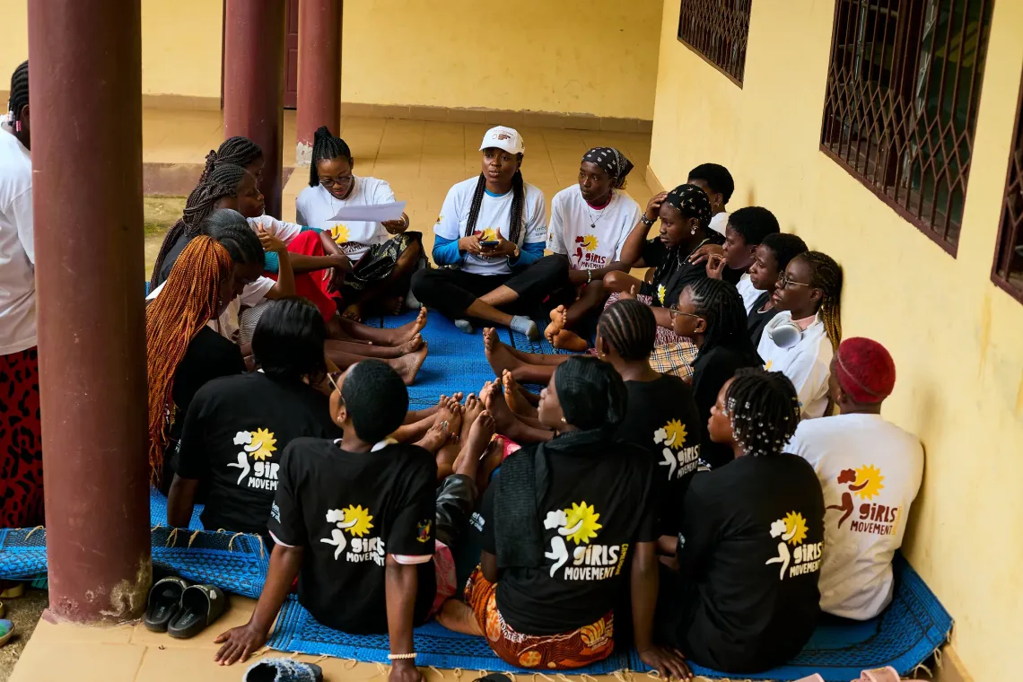 Group of Girls&rsquo; Movement participants seated in a circle on a mat, wearing black T-shirts with the movement&rsquo;s logo during a discussion session