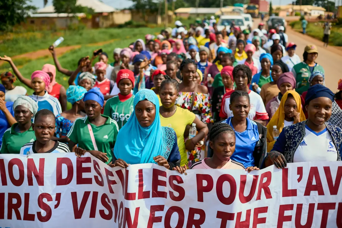 Large group of participants marching on a road holding a banner that reads &lsquo;Girls&rsquo; Vision for the Future&rsquo; during the Girls&rsquo; Movement Caravan