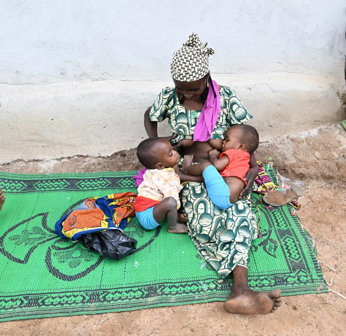 une maman assise sur une natte allaite ses jumeaux &agrave; l'est du Cameroun