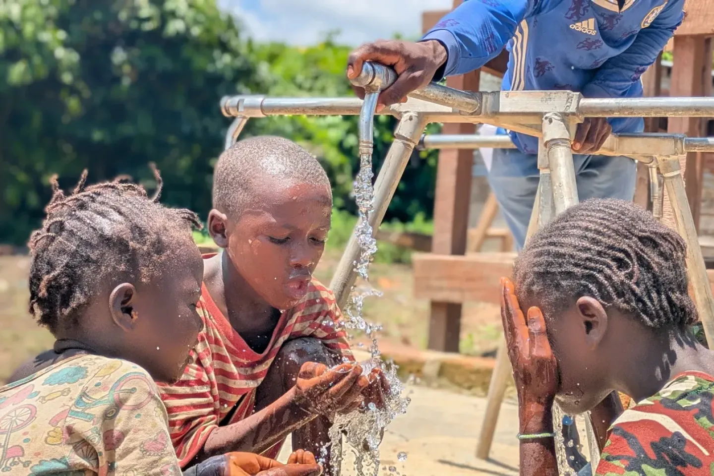 Children in Wayambo village refresh their face to ease the heat at the newly installed clean water facility. 