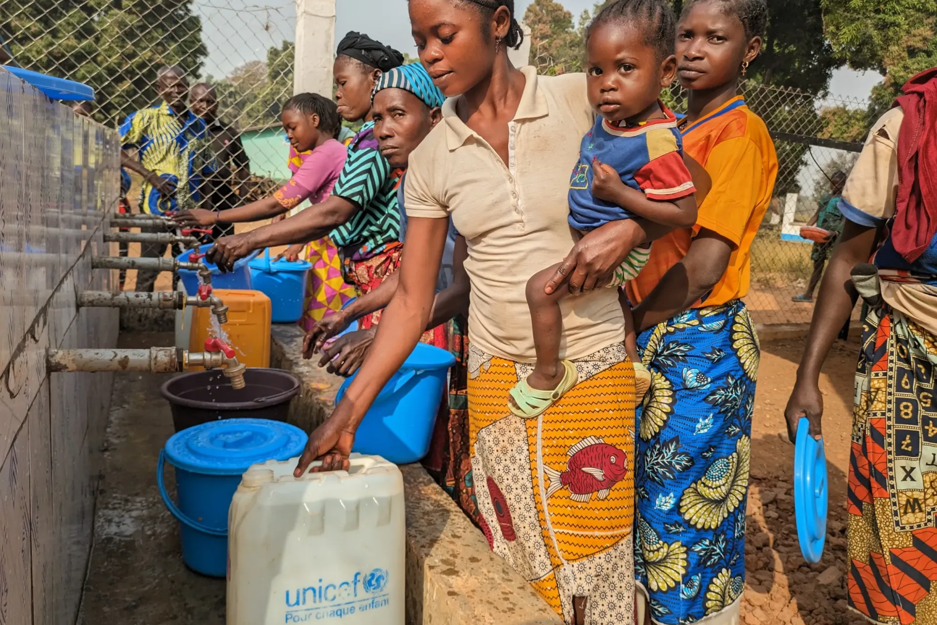 Women and children collect water with plastic jerrycans