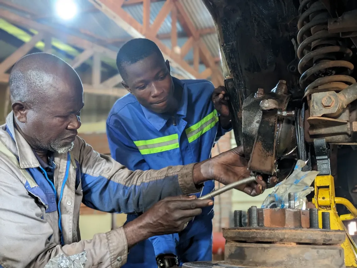 During his period of practice, Caleb follows the instructions given by an experienced mechanic. 