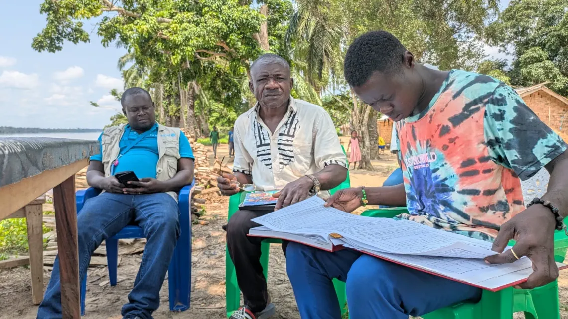 Jean Kaito, head of the Mondoli health centre, and his assistant, check the records of cholera cases and the dates in which they were discharged.  