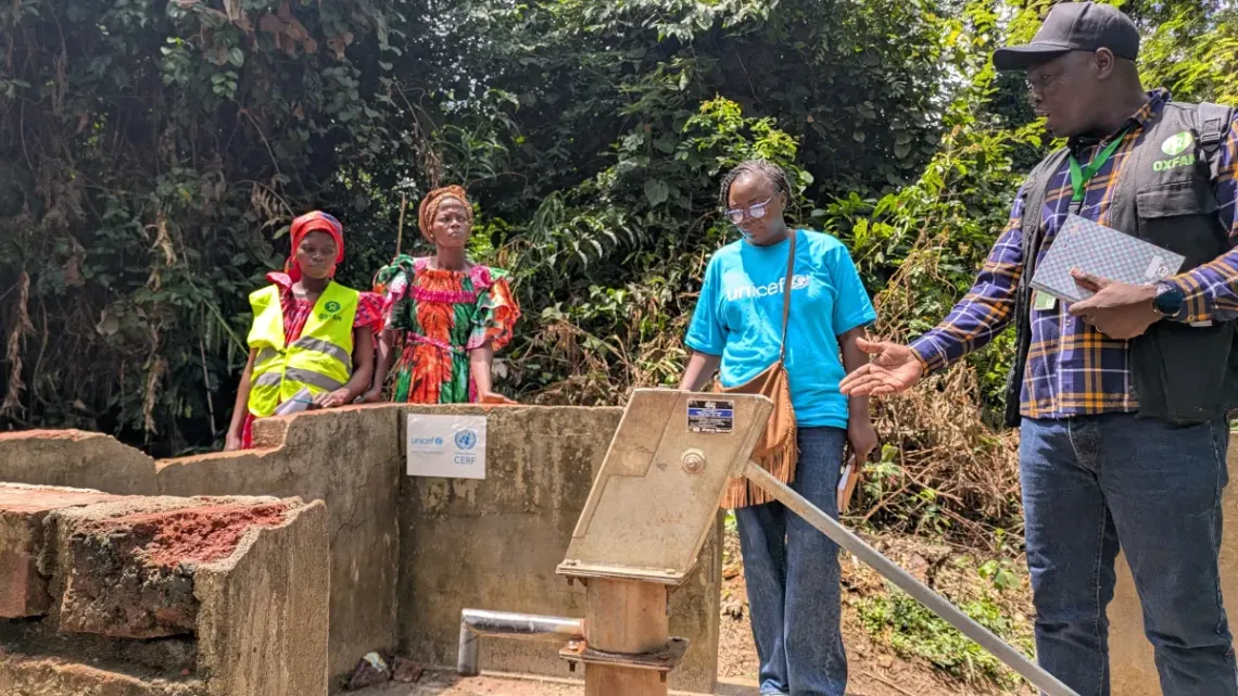 UNICEF and Oxfam workers examine the broken borehole in Bokassi 1 village, while Mureille Danemo and another woman look on. 