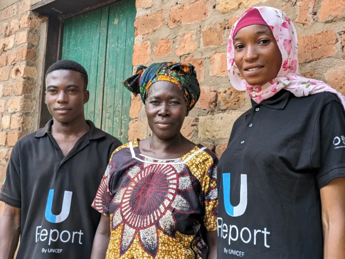 Zamzam and Agibael, U-Reporters, stand next to Antoinette. They handle cases of complaints by beneficiaries who feel that they humanitarian aid has not been properly managed