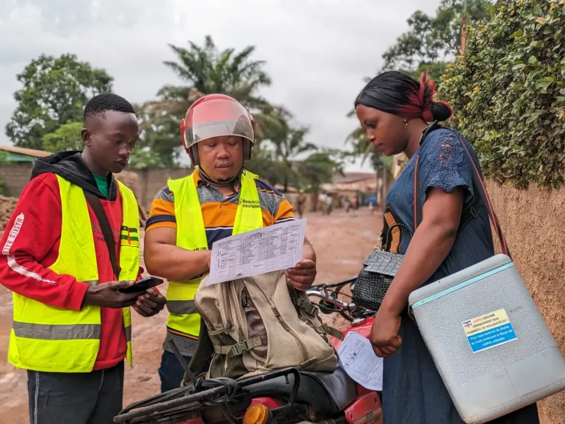Le Dr Johnny, responsable de la campagne de vaccination contre la polio dans le 8e arrondissement de Bangui, discute avec Mercie et Merveille avant que l'&eacute;quipe ne parte faire du porte-&agrave;-porte